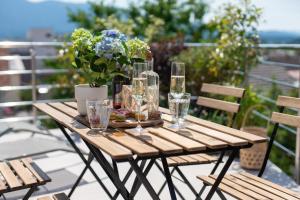 een houten tafel met glazen en een vaas met bloemen bij Villa Cerkniško jezero in Cerknica