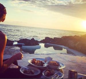 eine Person, die an einem Tisch mit zwei Teller Essen sitzt in der Unterkunft Tingalaya's Retreat in Negril