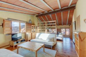 ein Wohnzimmer mit einem Sofa, einem Tisch und einem TV in der Unterkunft Can MartiPol in La Pobla de Lillet