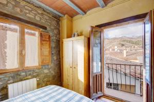 a bedroom with a balcony with a bed and a window at Can MartiPol in La Pobla de Lillet