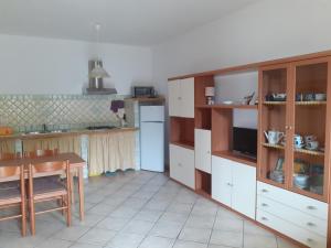 uma cozinha com armários brancos, uma mesa e um frigorífico em Casa Piana em Viddalba