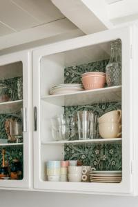 une armoire blanche remplie de vaisselle et d'assiettes dans l'établissement Logement Cornelia - Tholen, Zeeland, à Tholen