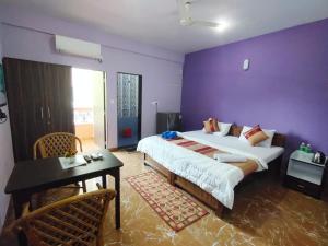 a bedroom with a large bed and a purple wall at The Narrow Way Edward Guest House in Candolim