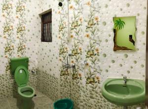 baño con aseo verde y lavamanos en The Narrow Way Edward Guest House, en Candolim