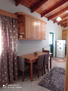 a kitchen with a wooden table and chairs and a refrigerator at Bratis House in Vartholomio