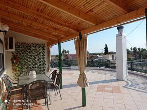 a patio with a table and chairs and a wooden roof at Bratis House in Vartholomio