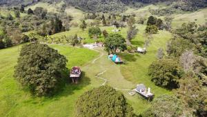 una vista aérea de un campo con tiendas de campaña y árboles en Glamping Reserva del Roble, en La Vega