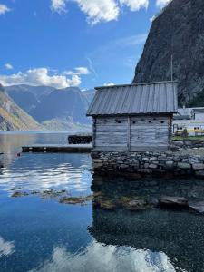 an old building on the water next to a mountain at Undredal Fjord Apartments in Undredal