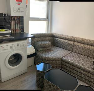 a kitchen with a couch and a washing machine at Beautiful First Floor one bedroom apartment B Walthamstow in London