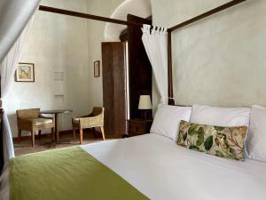 1 dormitorio con 1 cama y 1 mesa con silla en Hotel Boutique Posada Las Trampas, en Honda