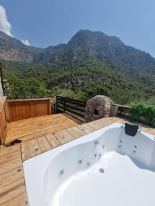 a bath tub on a deck with mountains in the background at Kabak Lost Forest VİLLA in Kızılcakaya