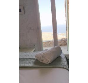 a towel sitting on a bed in front of a window at SIRENA in Kithnos