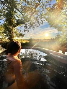 Nefoedd Romantic Shepherds Hut في سوانسي: رجل في حوض الاستحمام مع الشمس في الخلفية