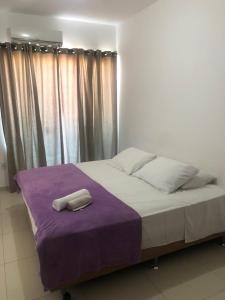 Una cama con una manta púrpura y una toalla. en Monte Libano Apart Hotel, en Florianópolis