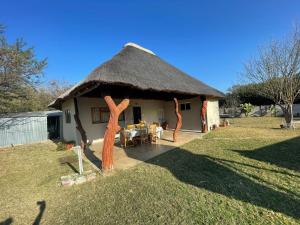 Cabaña pequeña con techo de paja y mesa en Vanross Self Catering Accommodation, en Thabazimbi