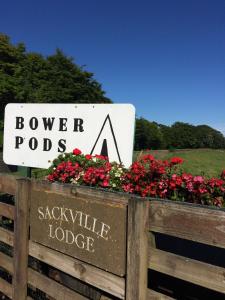 a sign for a dog park with red flowers at Bower Pods in Bowermadden