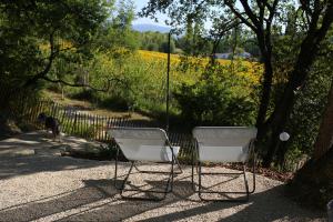 two chairs sitting in the shade next to a fence at L'Embellie, maisonnette tout confort en pleine nature in Suze