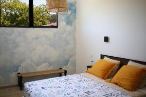 1 dormitorio con 1 cama con almohadas amarillas en L'Embellie, maisonnette tout confort en pleine nature, en Suze