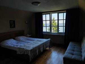 a bedroom with a bed and a window and a couch at Waterfront Villa Artvė with sauna - self check-in in Pervalka