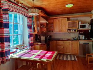 een keuken met houten kasten en een tafel en een raam bij Waterfront Villa Artvė with sauna - self check-in in Pervalka