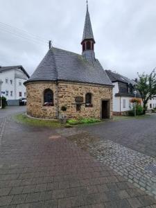 ein altes Backsteingebäude mit einem Kirchturm auf einer Straße in der Unterkunft Sternenhimmel-AW in Bad Neuenahr-Ahrweiler