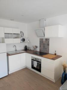 a white kitchen with a sink and a stove at Maison proche du centre ville in Pornic