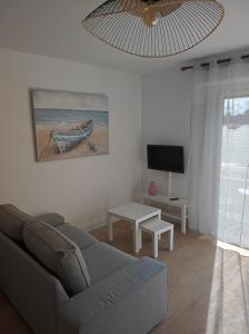 een woonkamer met een bank en een tv bij Maison proche du centre ville in Pornic