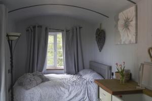 1 dormitorio con cama blanca y ventana en Nefoedd Romantic Shepherds Hut en Swansea