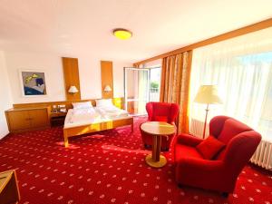 Habitación de hotel con sillas rojas, cama y mesa en Thermenhotel Tannenhof - Ihr Wohlfühl-Hotel en Bad Füssing
