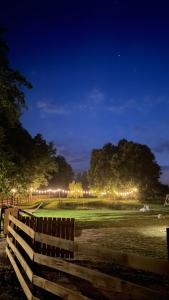 Ein Zaun auf einem Feld in der Nacht mit Lichtern in der Unterkunft Wypoczynek pod Lipami in Ruciane-Nida