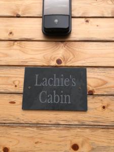 un cartello che legge il calio delle batterie seduto su un tavolo di legno di Lachie's Cabin a Portree