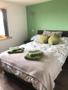 a bedroom with a bed with green towels on it at Lachie's Cabin in Portree