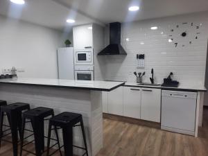 una cucina con elettrodomestici bianchi e sgabelli neri di Casa en vigo a 5 min playas a Vigo