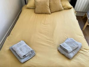 dos toallas están sentadas en una cama amarilla en *Lasuite #2 YELLOW*, en Valenciennes