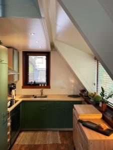 una cocina en el ático con armarios verdes y fregadero en Mimi's natuurhuisje, en Lanaken