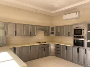 a large kitchen with gray cabinets and appliances at شاليه دانة الرس in Ar Rass