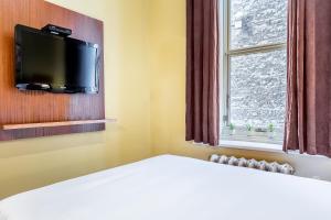a room with a bed with a tv and a window at Hotel Ermitage in Quebec City