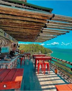 Tainha da Praia Aparthotel في بومبينهاس: مطعم بالطاولات الحمراء والمحيط في الخلفية