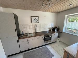 a kitchen with white cabinets and a sink and a window at Oxtown City Apartment in Ochsenhausen