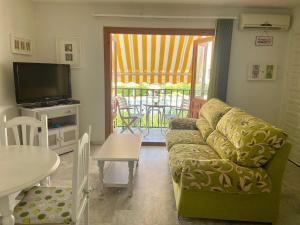 a living room with a couch and a tv and a table at Jardines Tropicales vera playa in Vera