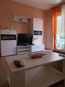 uma sala de estar com uma mesa, uma televisão e um sofá em Apartment Sunny Bulevar em Mostar