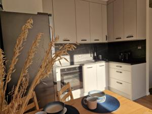 a kitchen with white cabinets and a table and a refrigerator at Apartament Iławianka in Iława