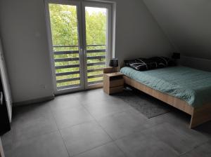 a bedroom with a bed and a large window at Willa w Brzozach Sznurki Spokojna 1 - Chmielno, Kaszuby, dom, jezioro in Chmielno