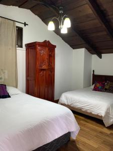 a bedroom with two beds and a wooden cabinet at Villa de Antaño in Antigua Guatemala