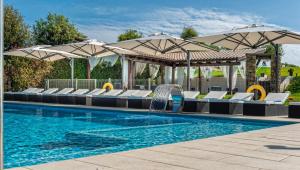 una piscina con sillas y sombrillas en Mas Rosset - Luxury Villa Girona - Costa Brava en Cornellá de Terri