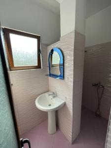 a bathroom with a sink and a window and a mirror at Centre Hotel in Berat