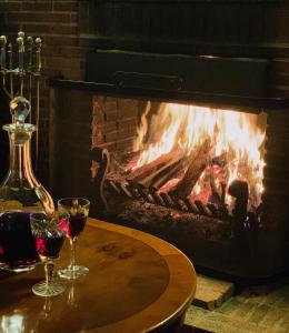 a fireplace with a table with two glasses of wine at KUBBA ROONGA GUESTHOUSE - Boutique Luxury Peaceful Stay & Gardens - Bed & Breakfast in Blackheath