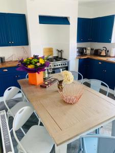 uma cozinha com armários azuis e uma mesa de madeira com flores em Funky cozy cottage with outside space em Eastbourne