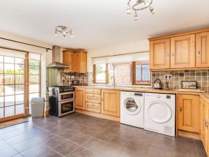 a kitchen with wooden cabinets and a washer and dryer at Wild Duck Lodge in Rufford