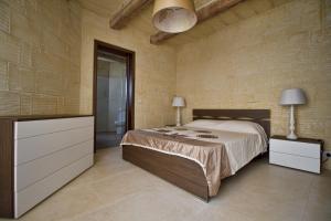 a bedroom with a bed and a dresser with two lamps at Villa Boomerang in Għasri